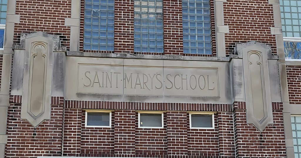 A brick building facade with large glass block windows and a stone sign reading 